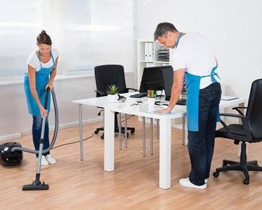 Two people cleaning a room with a vacuum.