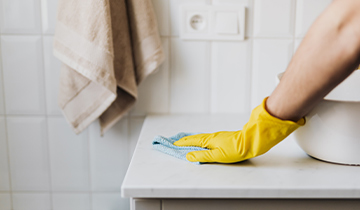 A person in yellow gloves cleaning the counter.