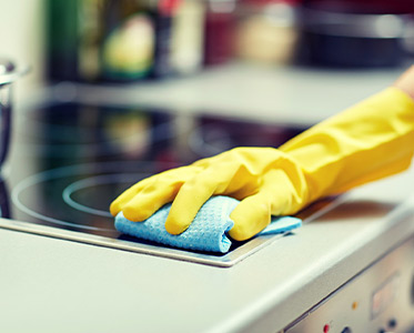 A person cleaning the top of an electric stove.